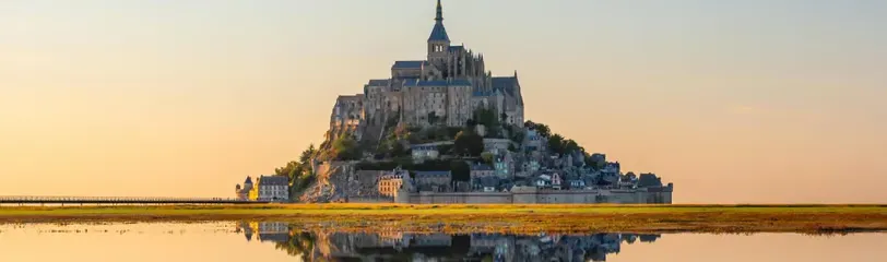 Murmures sacrés Mont Saint-Michel se reflétant dans l'eau au coucher du soleil, symbole des lieux sacrés et énergies vibratoires